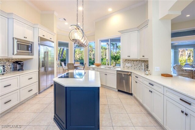 kitchen with a center island, built in appliances, crown molding, and light tile patterned floors