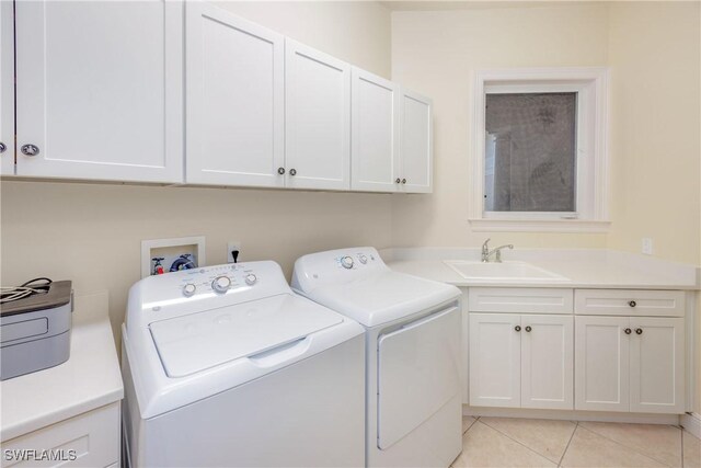 washroom featuring a sink, cabinet space, washing machine and dryer, and light tile patterned flooring