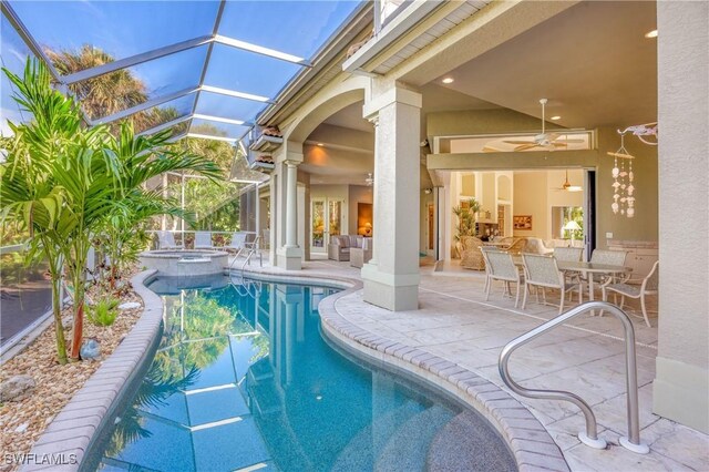 view of swimming pool featuring a pool with connected hot tub, a patio, glass enclosure, ceiling fan, and outdoor dining space