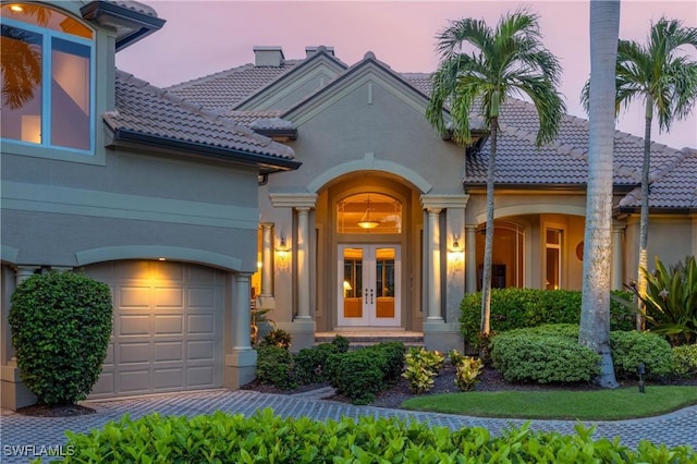 property entrance featuring french doors, a tiled roof, and stucco siding