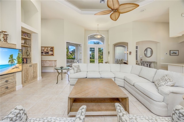 living room featuring ceiling fan, light tile patterned flooring, built in features, french doors, and a high ceiling