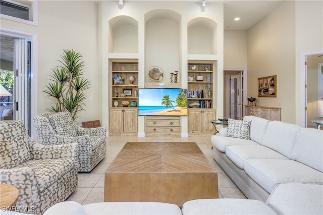 living room with a towering ceiling, light tile patterned flooring, and built in features