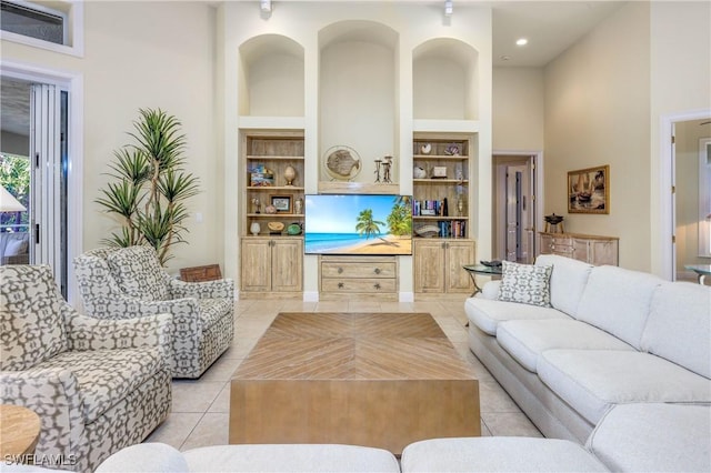 living area with a towering ceiling, built in features, recessed lighting, and light tile patterned floors