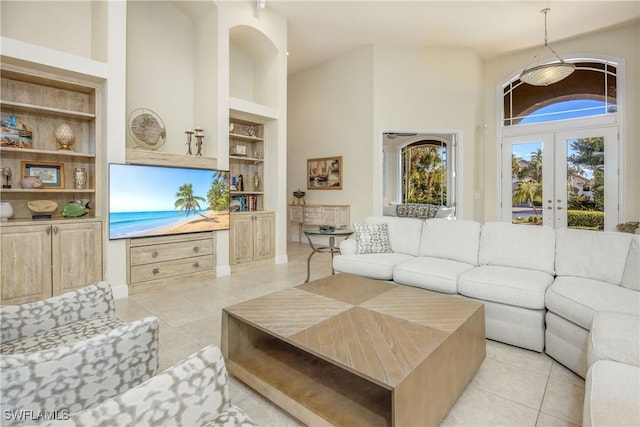 living area featuring light tile patterned flooring, built in features, french doors, and a towering ceiling