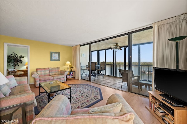 living room featuring light hardwood / wood-style flooring, expansive windows, and ceiling fan