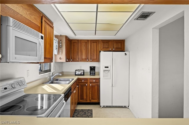 kitchen featuring sink, white appliances, and light tile patterned floors