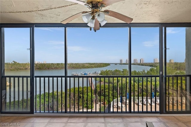 unfurnished sunroom featuring ceiling fan and a water view