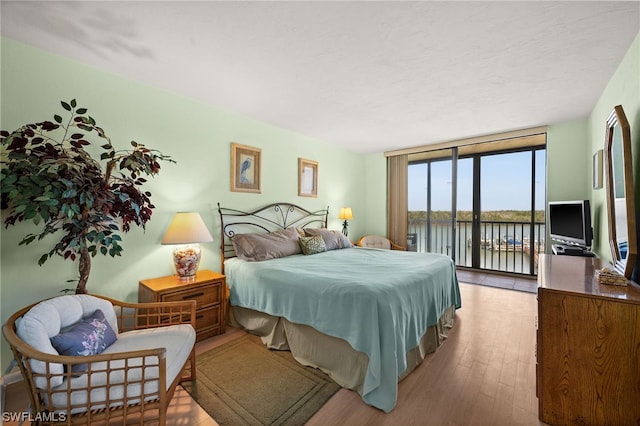 bedroom featuring hardwood / wood-style floors, expansive windows, and access to exterior