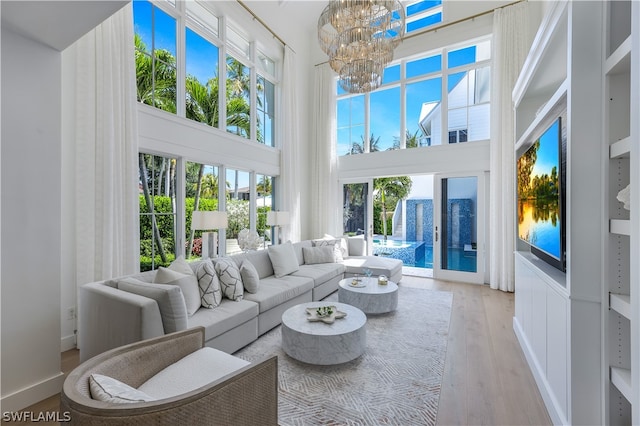 living room featuring a high ceiling, plenty of natural light, light hardwood / wood-style flooring, and a notable chandelier