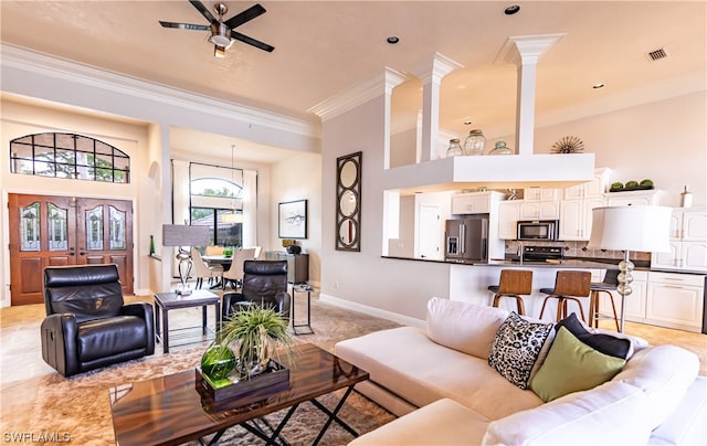 living room featuring ceiling fan, ornamental molding, and decorative columns