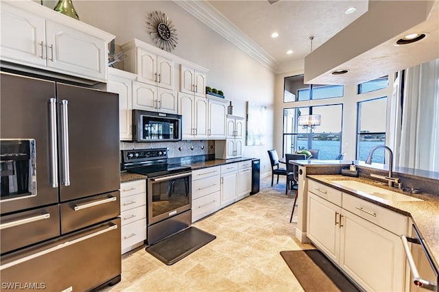 kitchen featuring dark stone countertops, crown molding, appliances with stainless steel finishes, sink, and pendant lighting