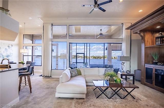 living room with a water view, ceiling fan, sink, and ornamental molding