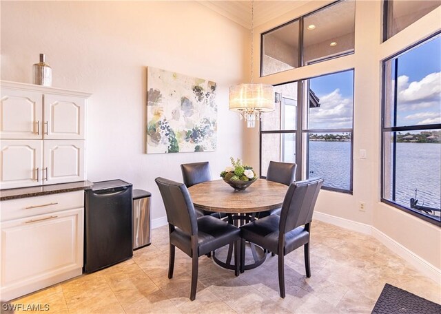 dining room featuring a towering ceiling, a notable chandelier, and a water view