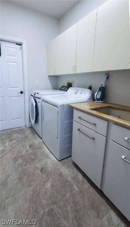 laundry room featuring washer and dryer and cabinets