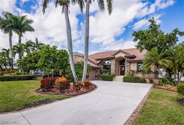 mediterranean / spanish-style home featuring a garage and a front lawn