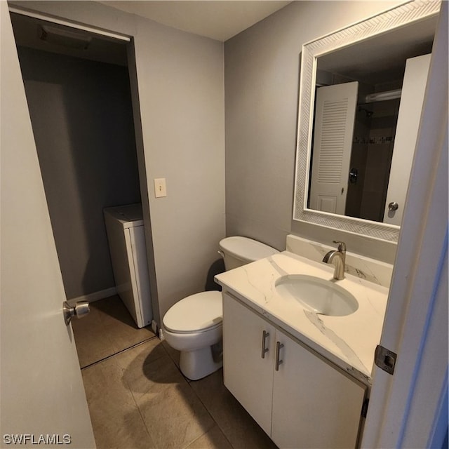 bathroom featuring washer / dryer, vanity, tile patterned flooring, and toilet