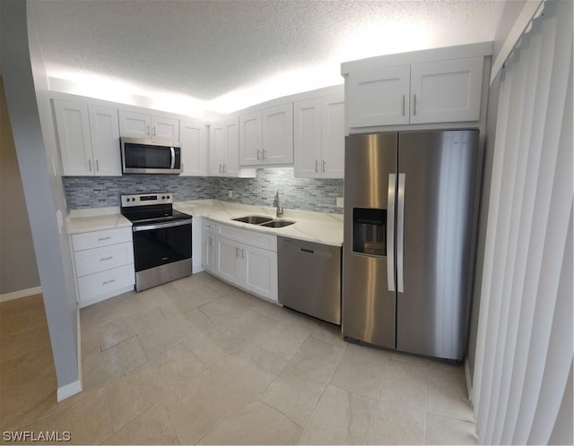 kitchen with a sink, tasteful backsplash, a textured ceiling, stainless steel appliances, and white cabinets