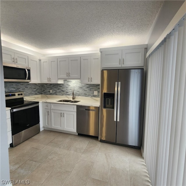 kitchen with backsplash, stainless steel appliances, sink, and light tile patterned floors