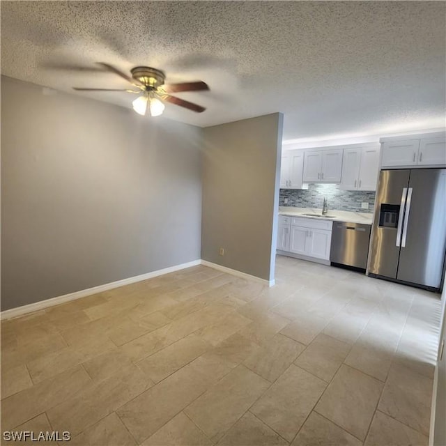 kitchen with tasteful backsplash, ceiling fan, light countertops, appliances with stainless steel finishes, and a sink