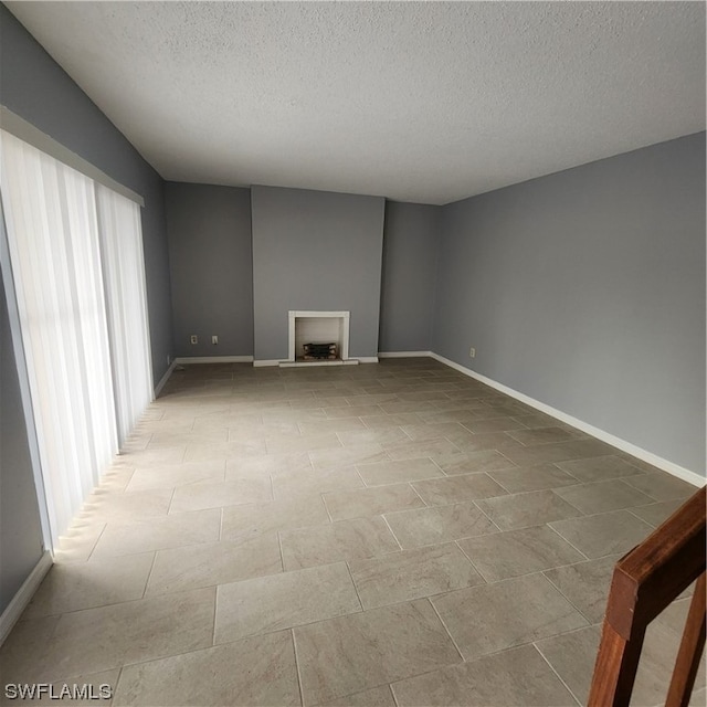 tiled empty room featuring a textured ceiling and a wealth of natural light