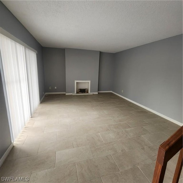 spare room with a textured ceiling and baseboards