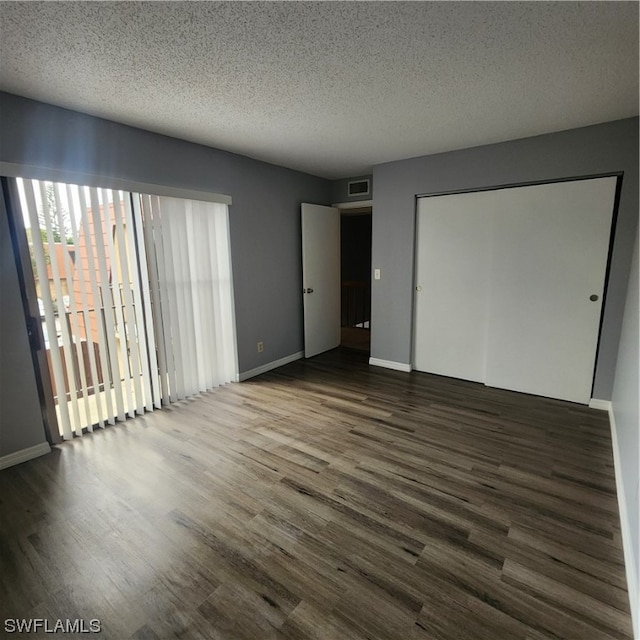 unfurnished bedroom featuring wood-type flooring, a textured ceiling, and a closet