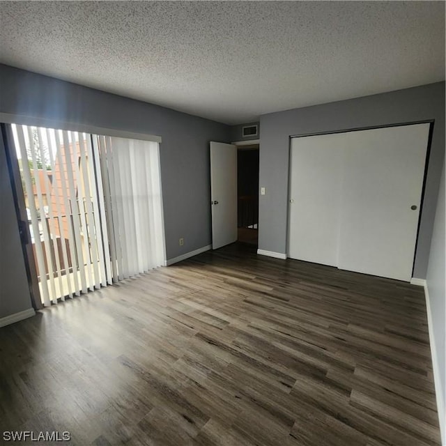 unfurnished bedroom with visible vents, a textured ceiling, baseboards, and wood finished floors