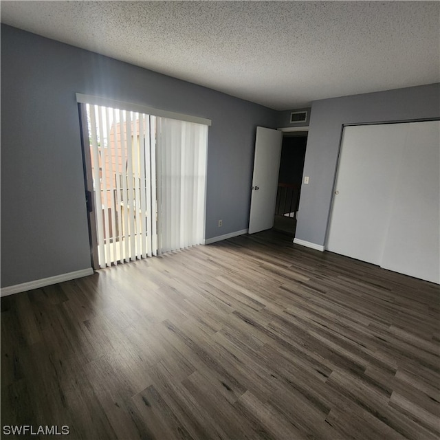 unfurnished bedroom featuring dark wood-type flooring, a textured ceiling, and a closet