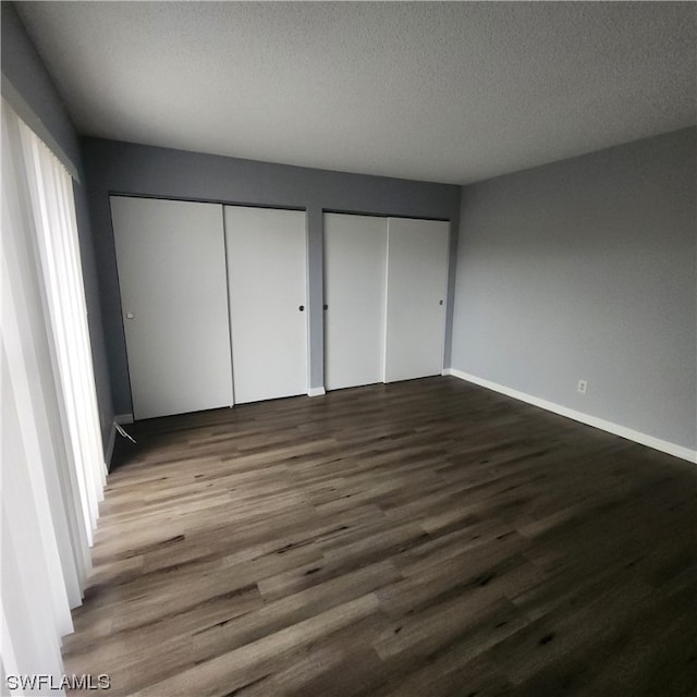 unfurnished bedroom with two closets, wood-type flooring, and a textured ceiling