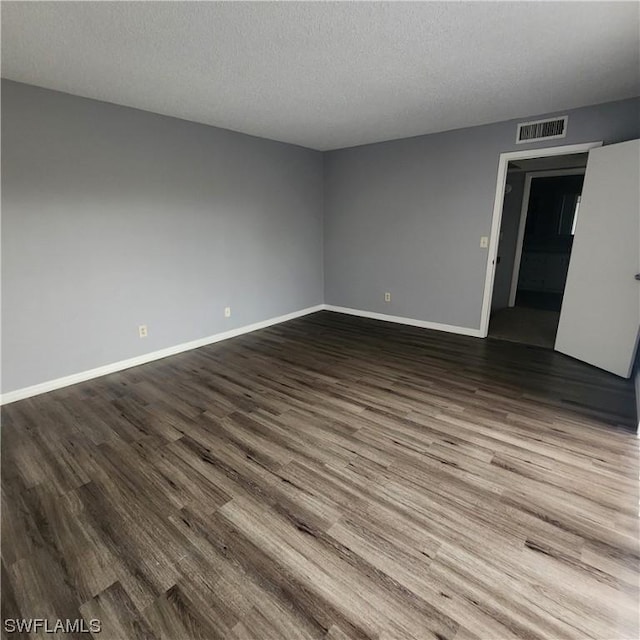 unfurnished room featuring visible vents, baseboards, a textured ceiling, and dark wood-style floors