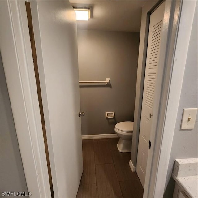 bathroom with vanity, toilet, baseboards, and wood finish floors