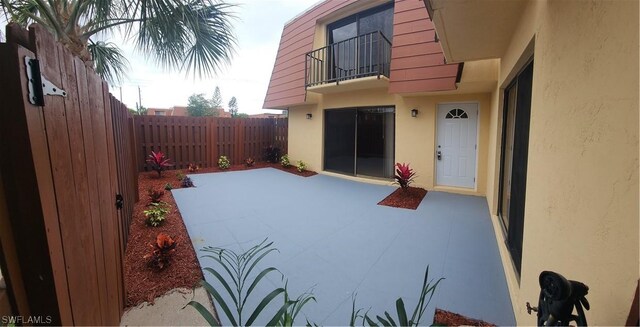 view of patio featuring a balcony and a fenced backyard