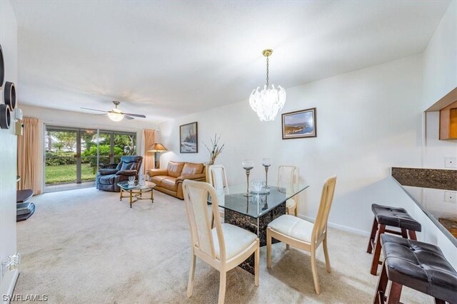 carpeted dining space with ceiling fan with notable chandelier