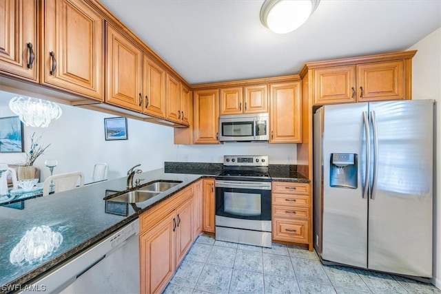 kitchen featuring appliances with stainless steel finishes, dark stone countertops, light tile patterned floors, and sink