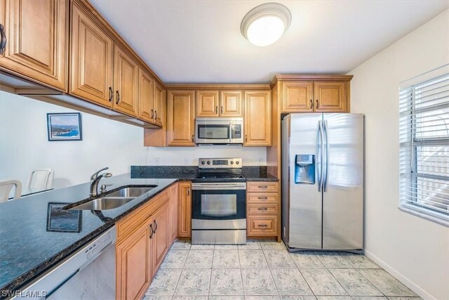 kitchen featuring light tile patterned flooring, sink, stainless steel appliances, and dark stone countertops