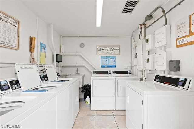 washroom with washing machine and dryer, sink, and light tile patterned floors