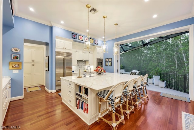 kitchen featuring dark wood-style flooring, crown molding, visible vents, appliances with stainless steel finishes, and a kitchen breakfast bar