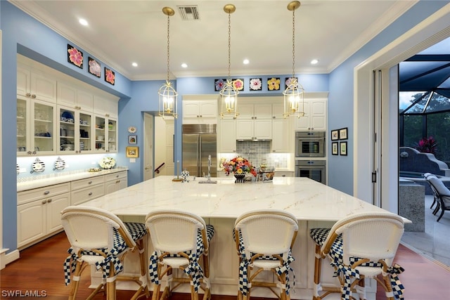 kitchen with decorative light fixtures, dark hardwood / wood-style floors, ornamental molding, appliances with stainless steel finishes, and a large island