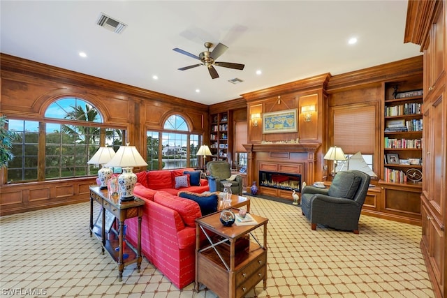 living room featuring ceiling fan, wood walls, ornamental molding, and light carpet