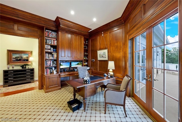 home office with french doors, ornamental molding, built in shelves, built in desk, and wood walls