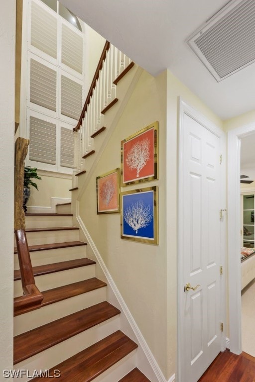 stairway with baseboards, visible vents, and wood finished floors