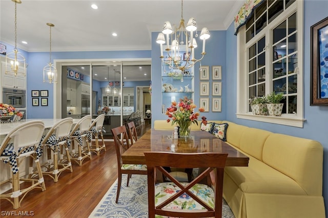 dining area with hardwood / wood-style floors, ornamental molding, and a chandelier