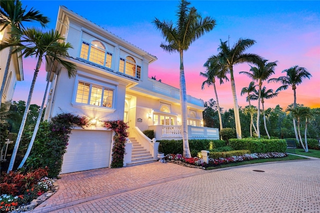 mediterranean / spanish-style home with stairway, decorative driveway, an attached garage, and stucco siding