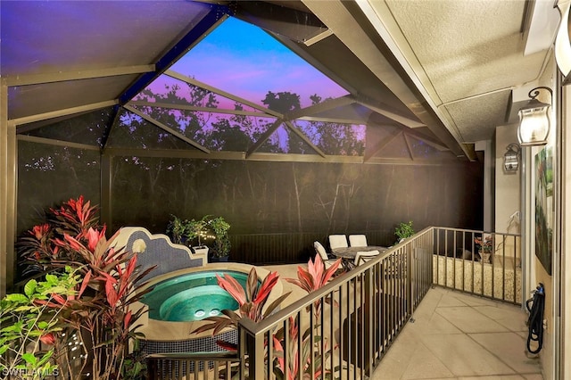 balcony at dusk with a sunroom and an outdoor hot tub