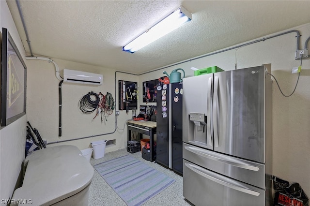 kitchen with a textured ceiling, speckled floor, stainless steel refrigerator with ice dispenser, and a wall mounted air conditioner