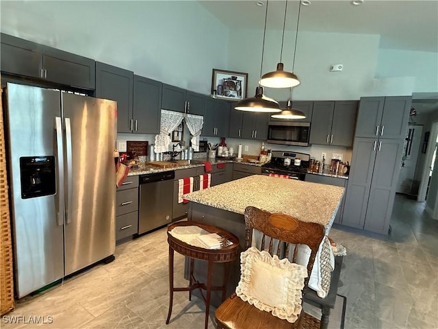 kitchen featuring a center island, a sink, a towering ceiling, stainless steel appliances, and pendant lighting