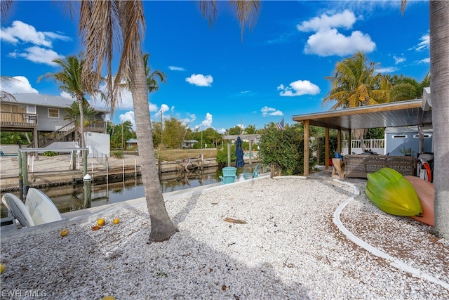 view of yard featuring a patio, a dock, and a water view