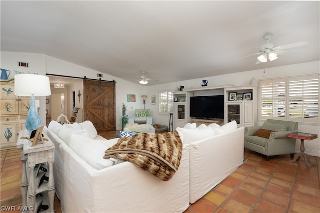 living room with a barn door, ceiling fan, and vaulted ceiling