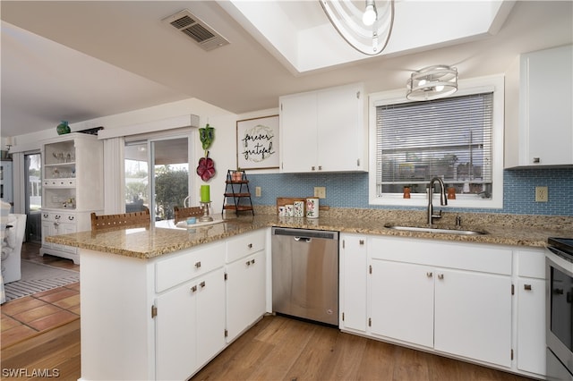 kitchen with decorative backsplash, kitchen peninsula, stainless steel appliances, sink, and white cabinets