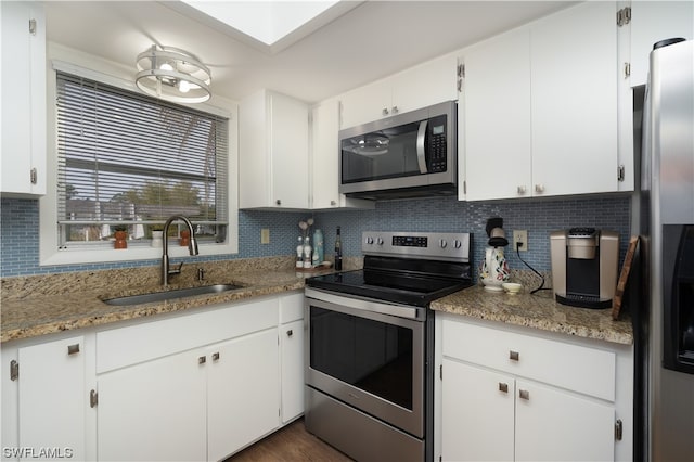 kitchen featuring light stone countertops, sink, backsplash, white cabinetry, and stainless steel appliances